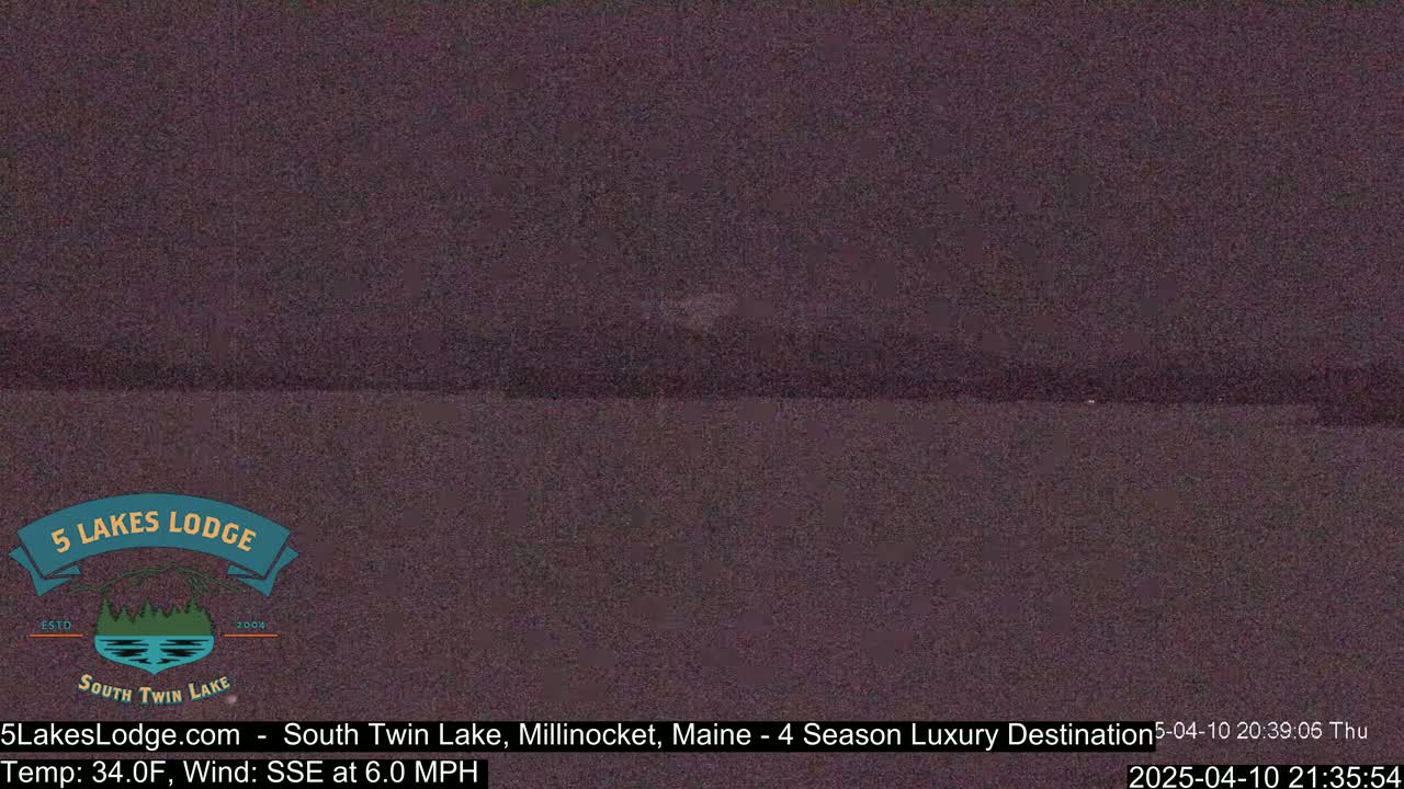 A dark, blurry view of a lake at night under a dark sky.