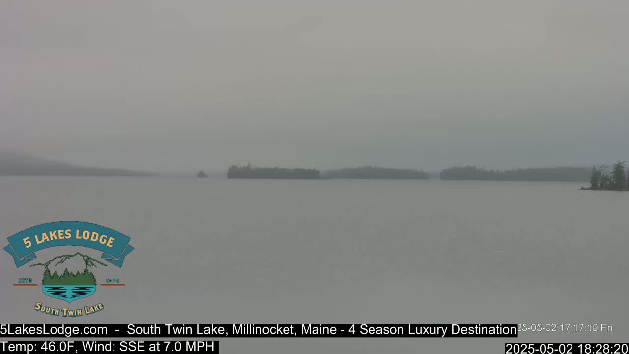 A hazy, overcast view shows a calm lake with several small wooded islands in the distance.