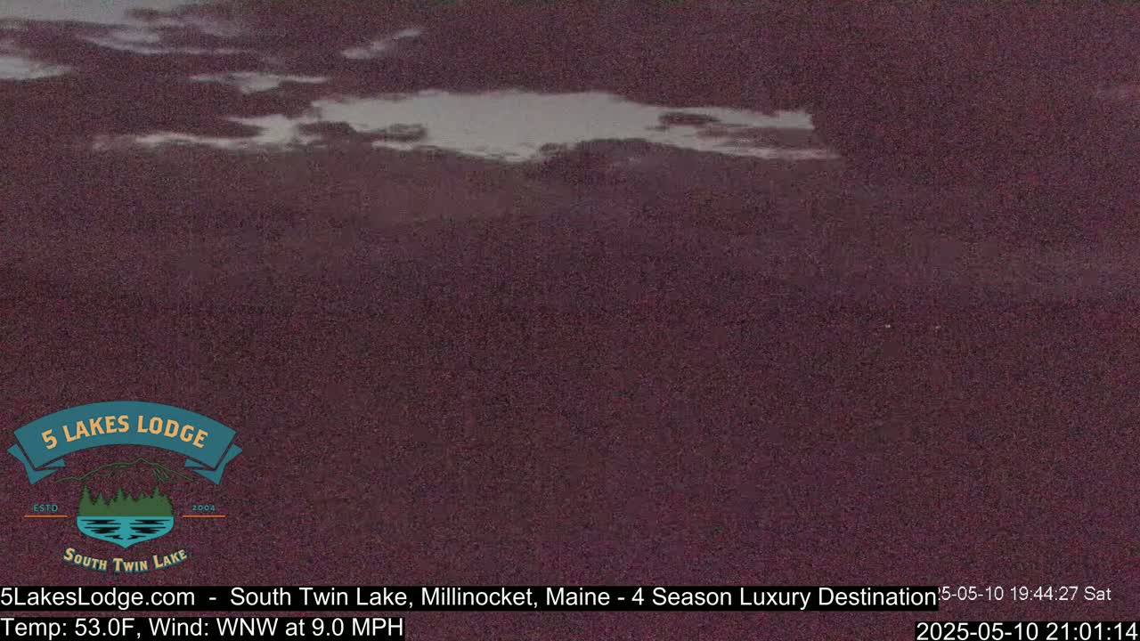 A dark, mostly cloudy night scene shows a body of water under a somewhat clear area of sky.