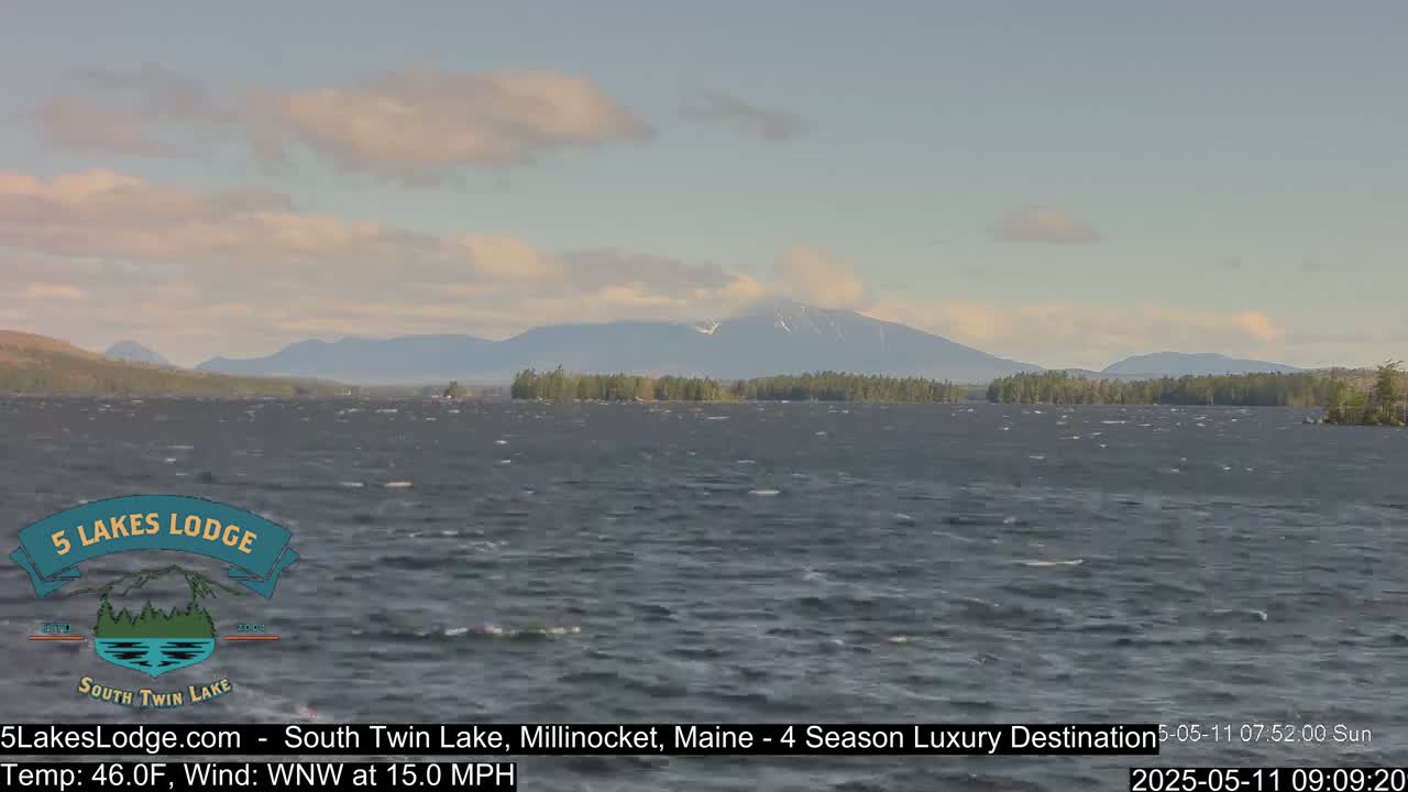 A choppy lake with a distant mountain range under a partly cloudy sky.