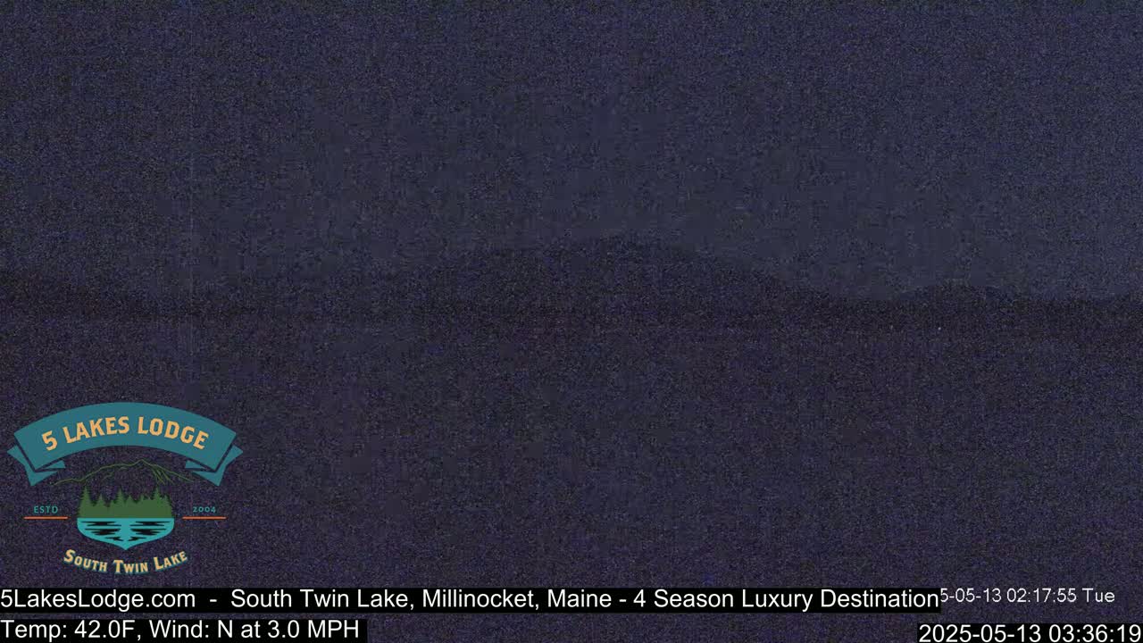 A dark, nighttime scene of a lake is shown under a clear sky.