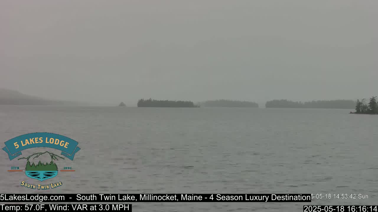 A hazy, gray day shows a calm lake with several small, distant islands under an overcast sky.