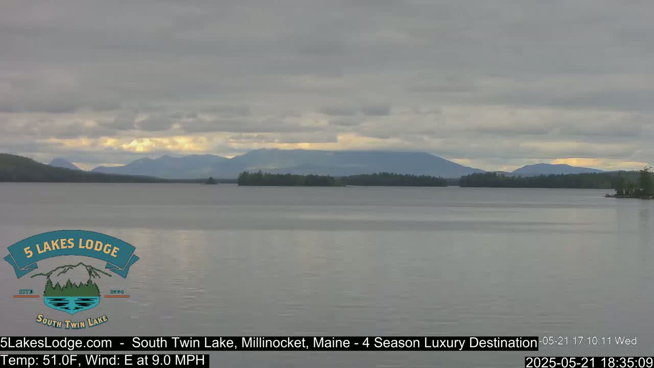 A calm lake with distant mountains under an overcast sky.