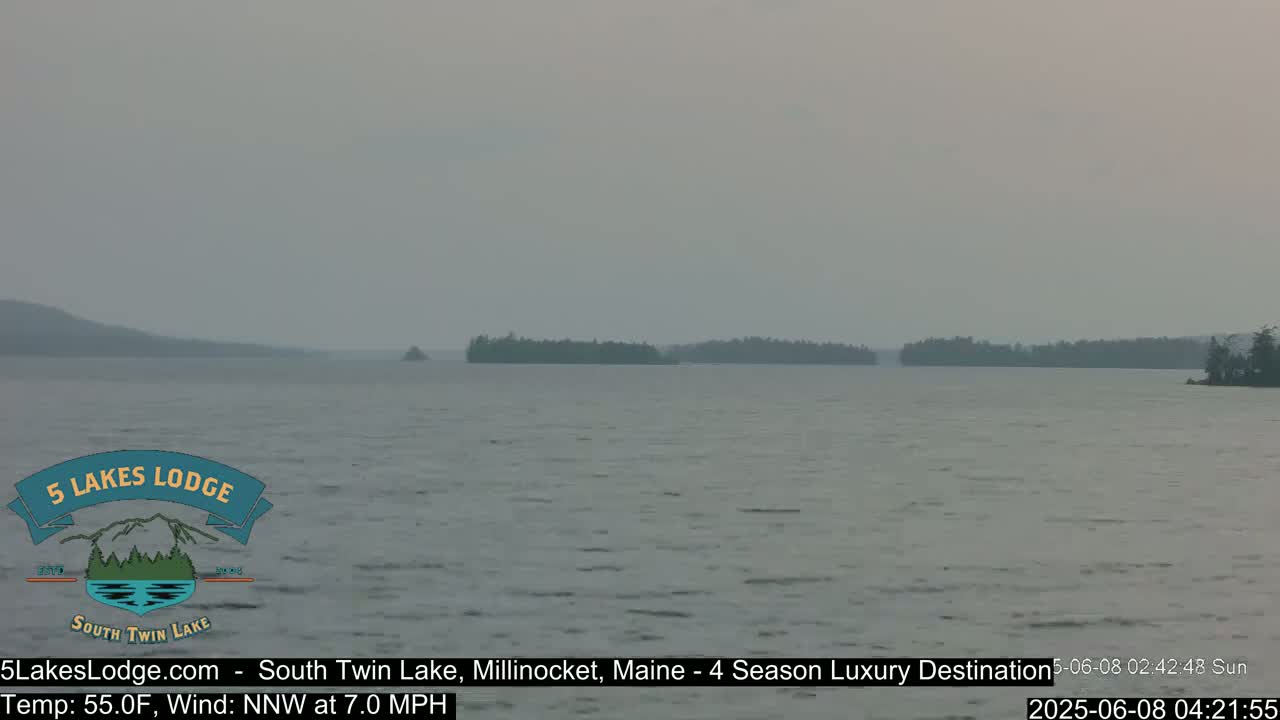 A hazy view of a lake with small islands in the distance under a gray sky.