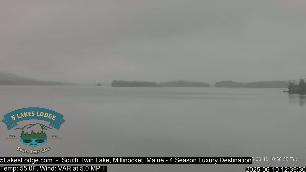 A hazy, gray day shows a calm lake with dark tree lines on the far shore.