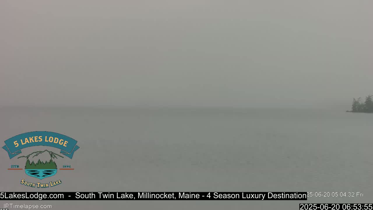 A hazy, gray lake is visible, with a small island of trees in the distance.