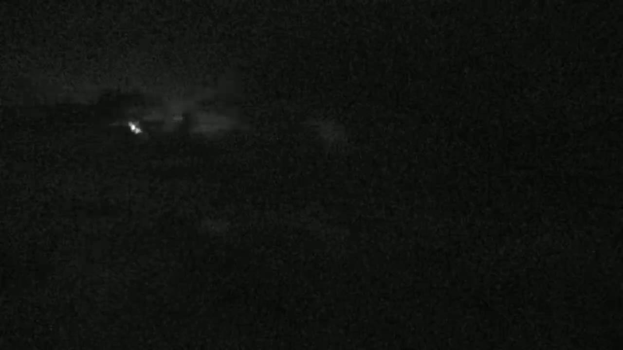 A dark, nighttime scene shows a faint, blurry light in the distance, possibly lightning.