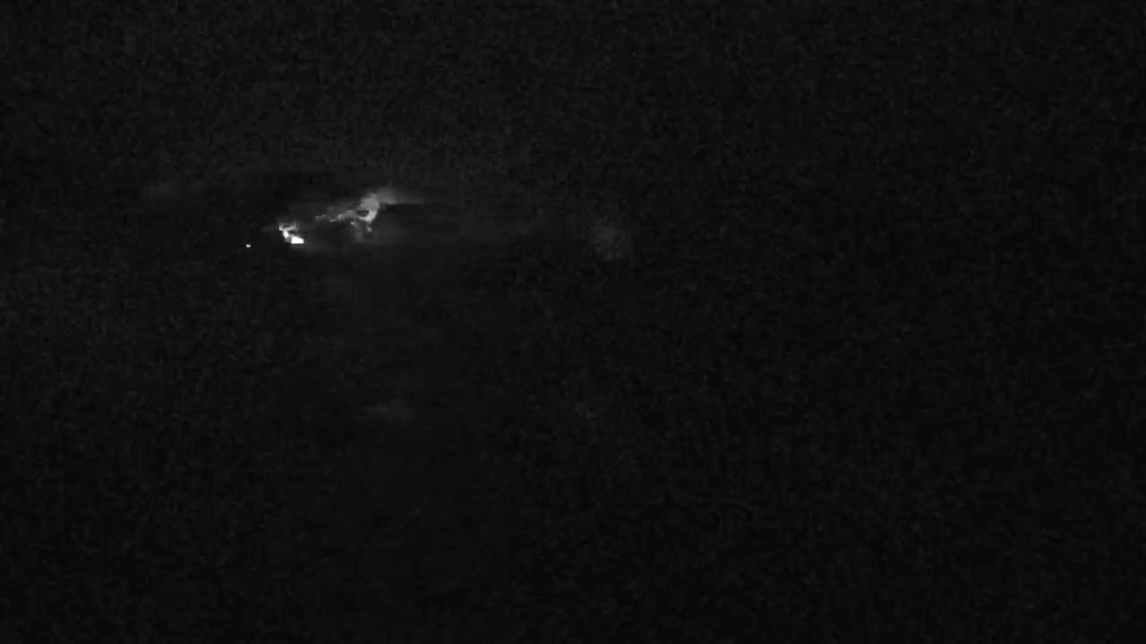 A nighttime scene shows a lightning strike in a dark, cloudy sky.