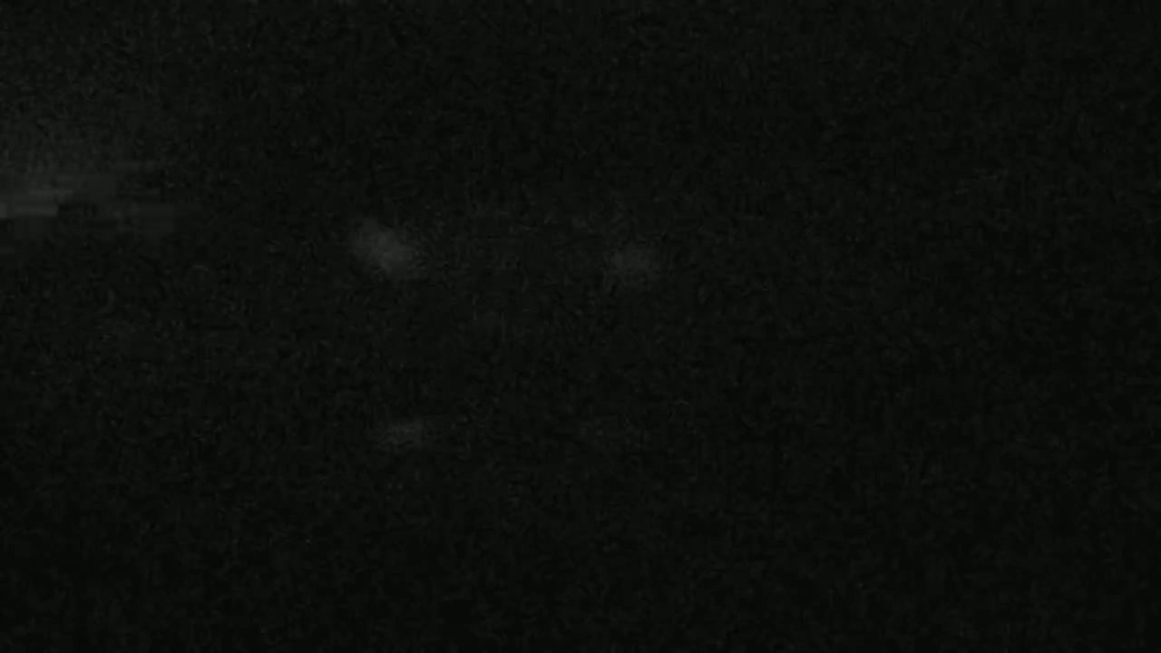 The image shows a dark, textured surface with subtle variations in shading and a few faint, lighter spots.