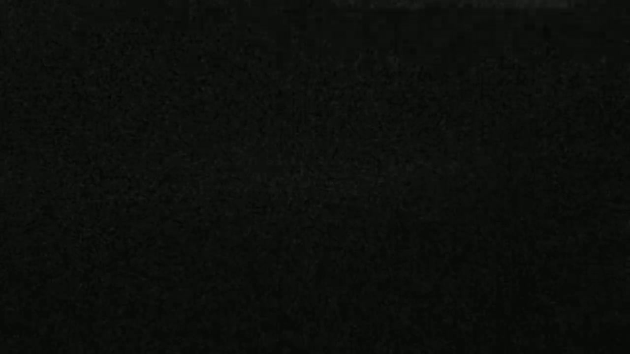 The image shows a dark, textured surface that appears to be a close-up of dark-colored material.