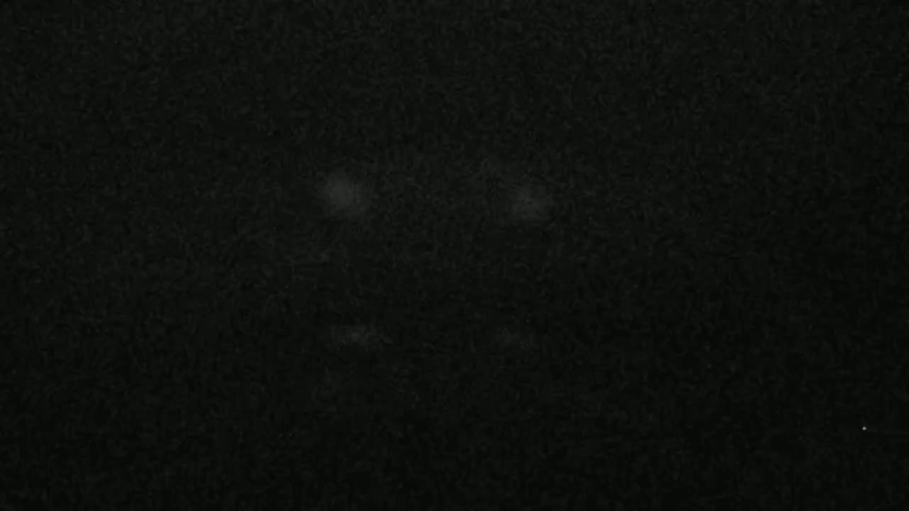 A dark, textured surface with several faint, lighter spots.