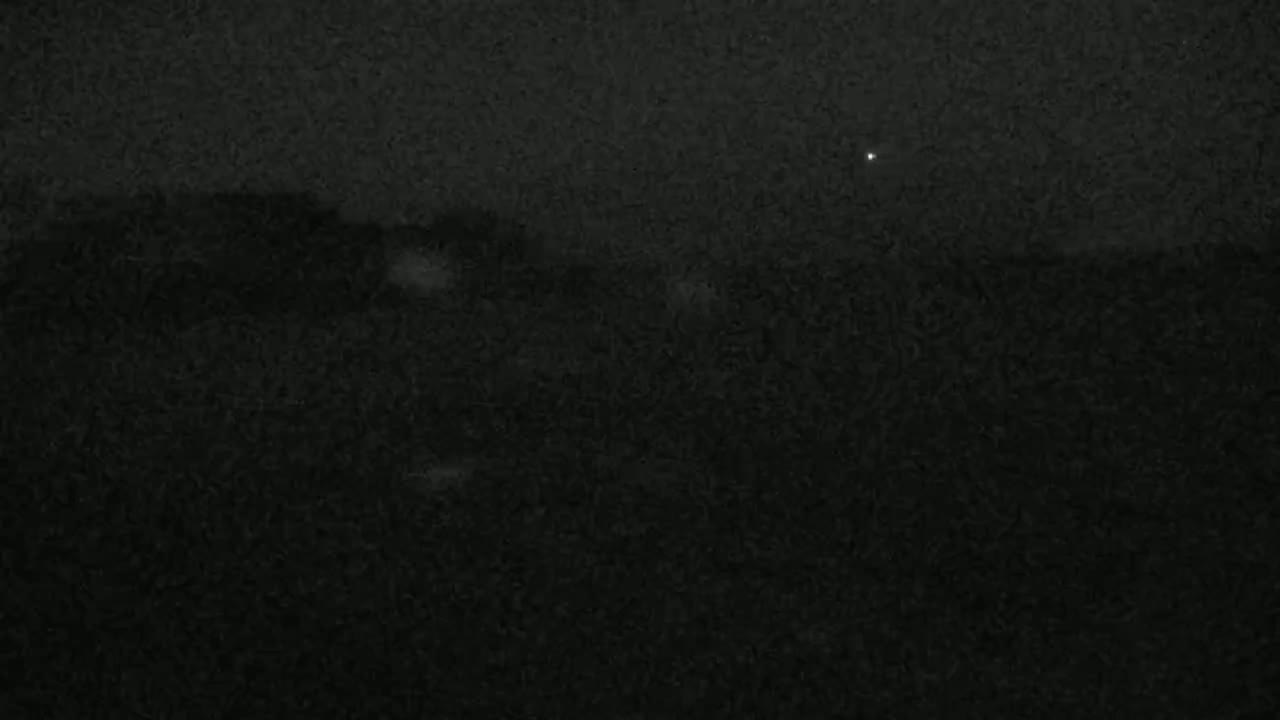 A dark, possibly nighttime, outdoor scene with a few faint lights visible in the distance.