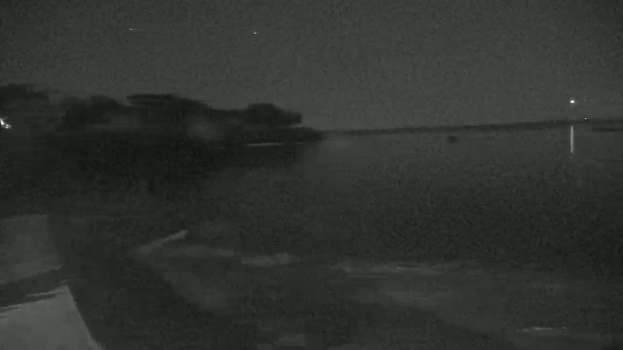 A nighttime view shows dark land meeting a dark body of water under a clear, dark sky.