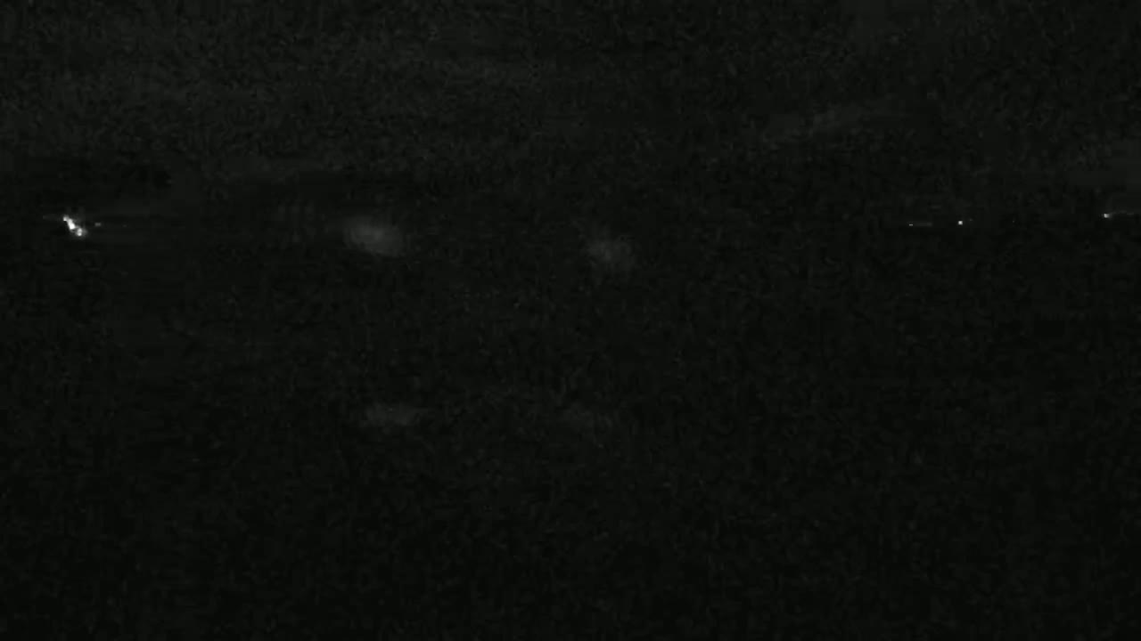 A nighttime, dark scene shows faintly lit objects in the distance.