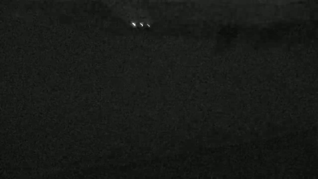 Two pairs of headlights are visible on a dark, possibly nighttime, road.
