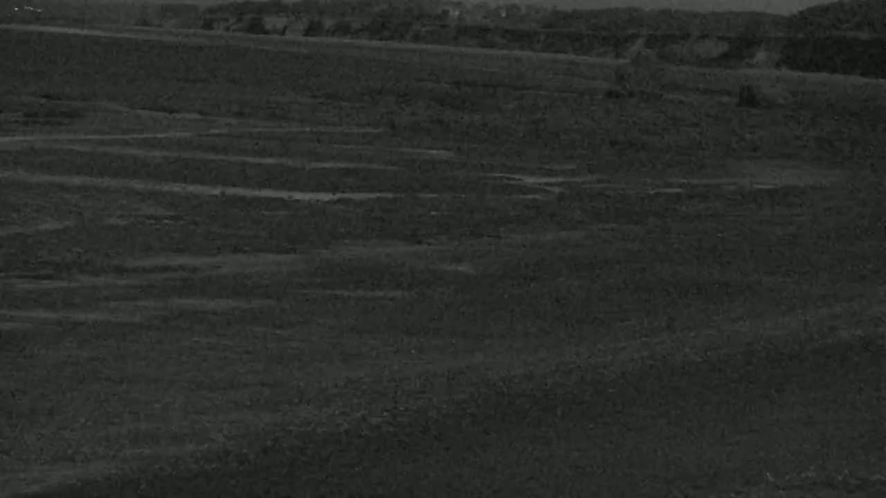 A dark, seemingly barren landscape stretches across the image under what appears to be a nighttime or low-light sky.