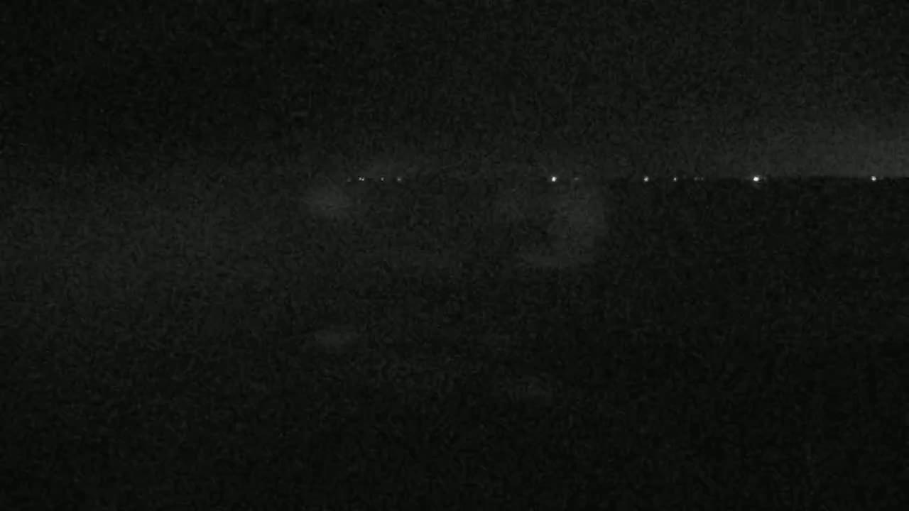 A dark, nighttime scene shows a distant line of faint lights on the horizon.