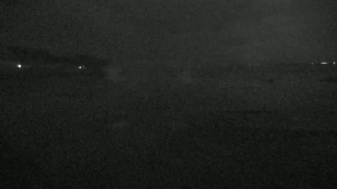 A dark, grainy nighttime landscape shows a few distant, faint lights on the horizon.