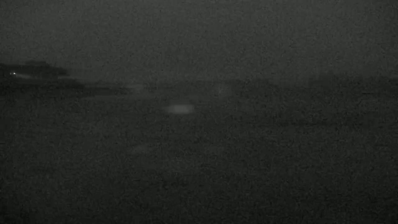 A dark, blurry image shows a nighttime scene of a flat, dark landscape under a hazy sky.