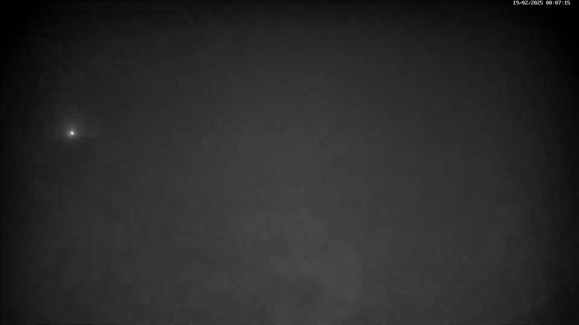 A faint, bright light is visible in a dark, nighttime sky.
