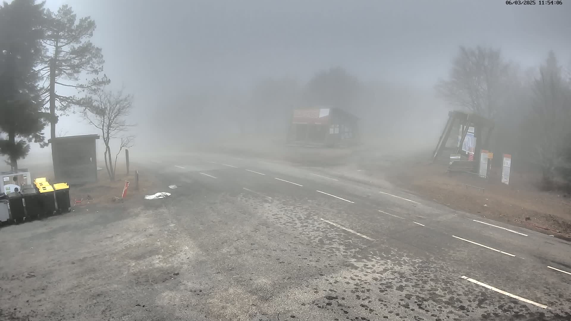 A foggy road intersection is visible, with a few buildings and trees barely discernible through the dense fog.