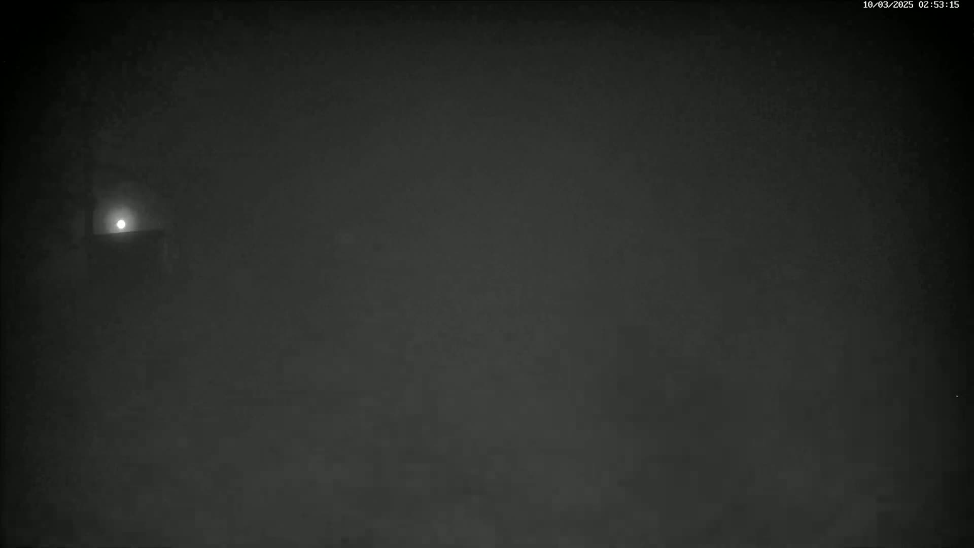 A dimly lit, foggy scene at night shows a faint light source in the upper left corner.