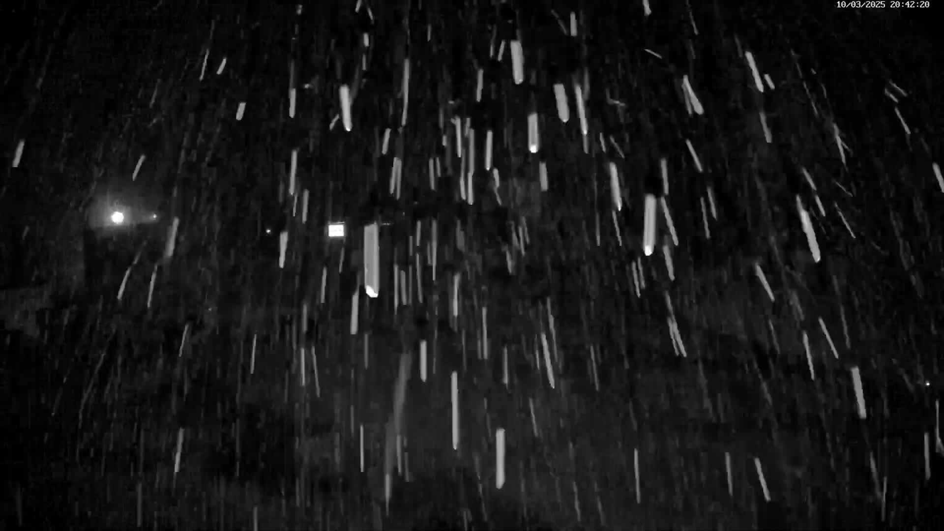 A nighttime scene shows heavy snowfall with faintly visible lights in the distance.