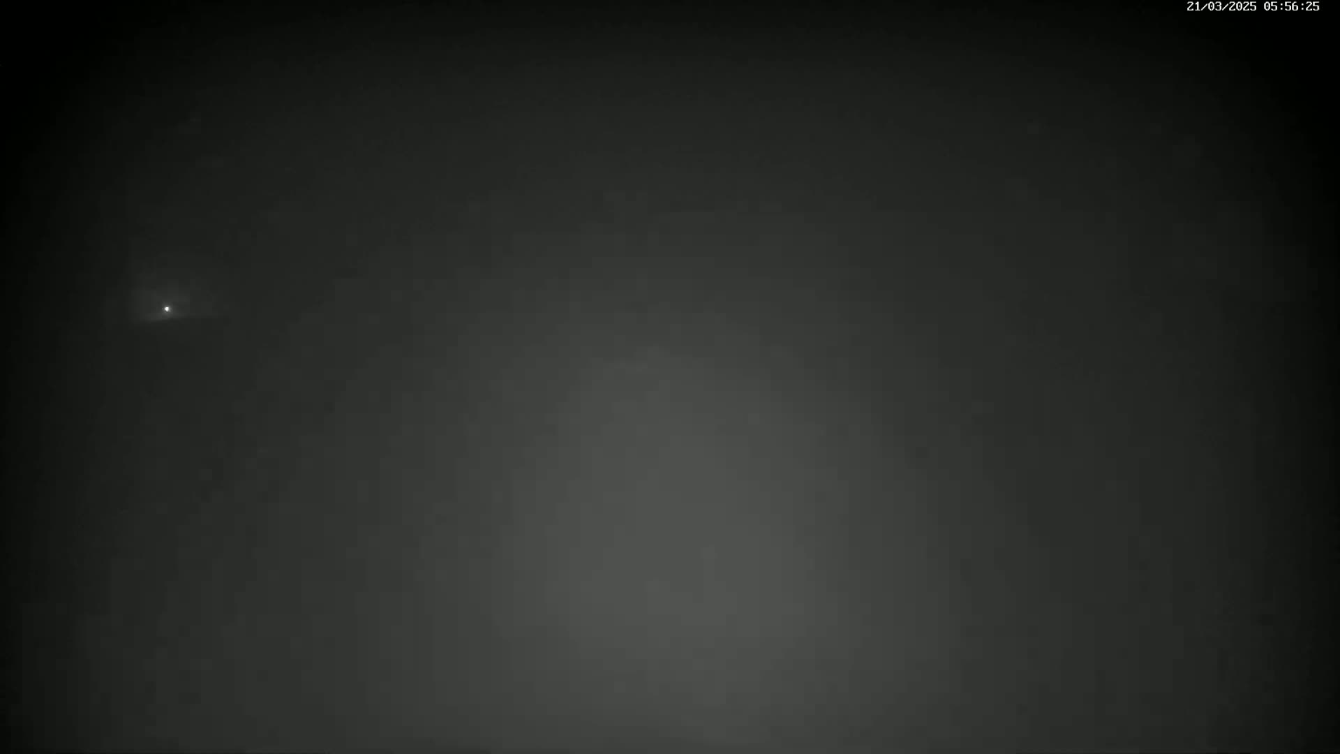 A faint light is visible in a dark, foggy night sky.