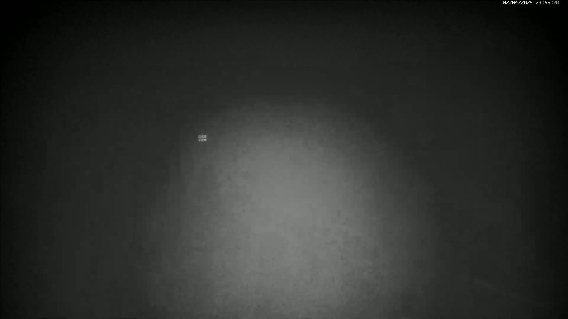 A grainy, dark gray image shows a lighter gray area in the center, suggesting a dimly lit space.