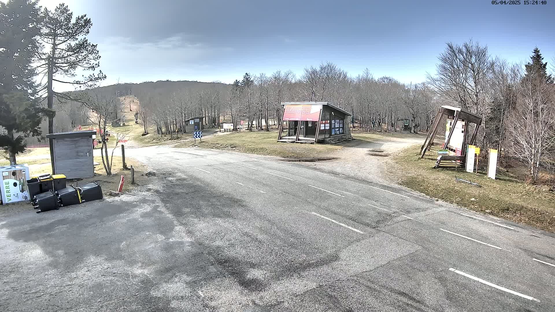 A paved road leads to a ski area with several small buildings and signage under a mostly clear, sunny sky.