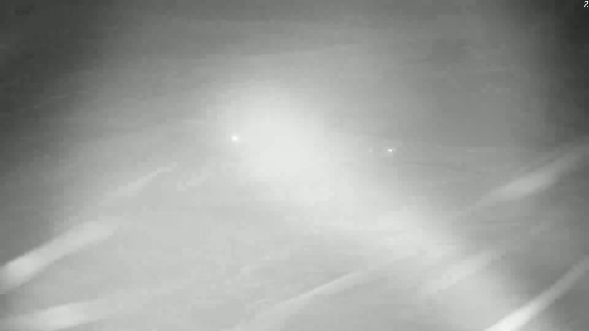 A blurry, grayscale image shows faint lights in the distance through heavy fog or mist at night.