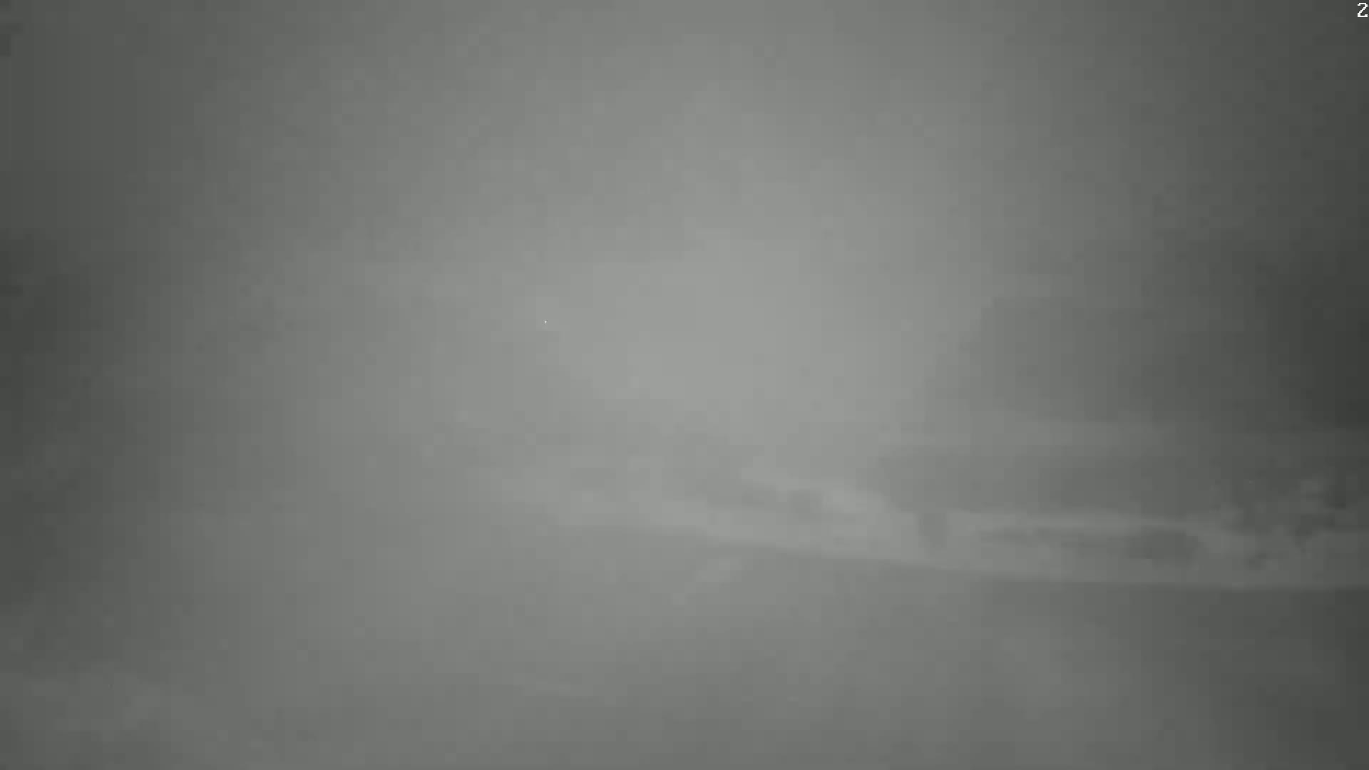 A blurry, low-visibility image shows a foggy or hazy scene with indistinct shapes in the mid-ground.