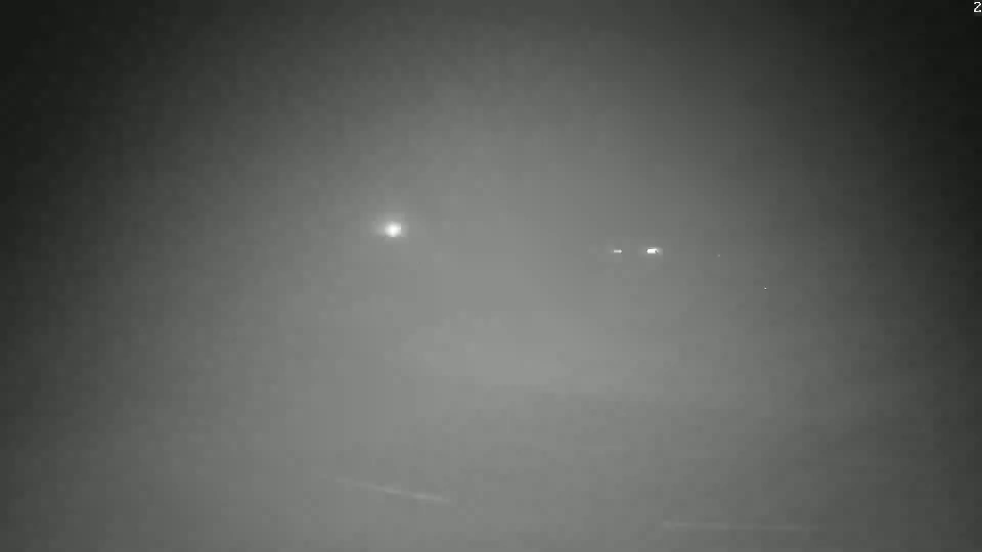 Faint lights are visible through a thick fog at night.