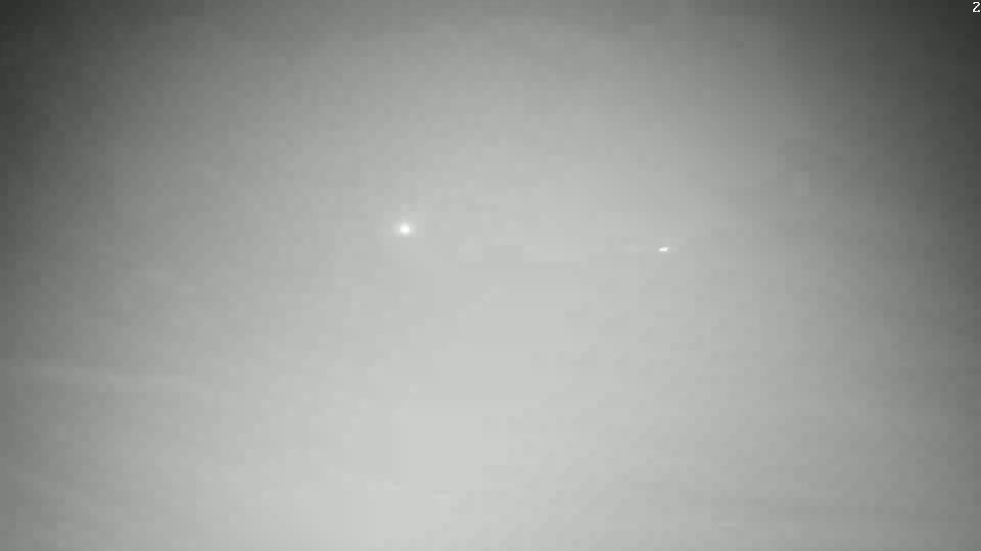 A hazy, gray outdoor scene shows two faint lights in the distance.