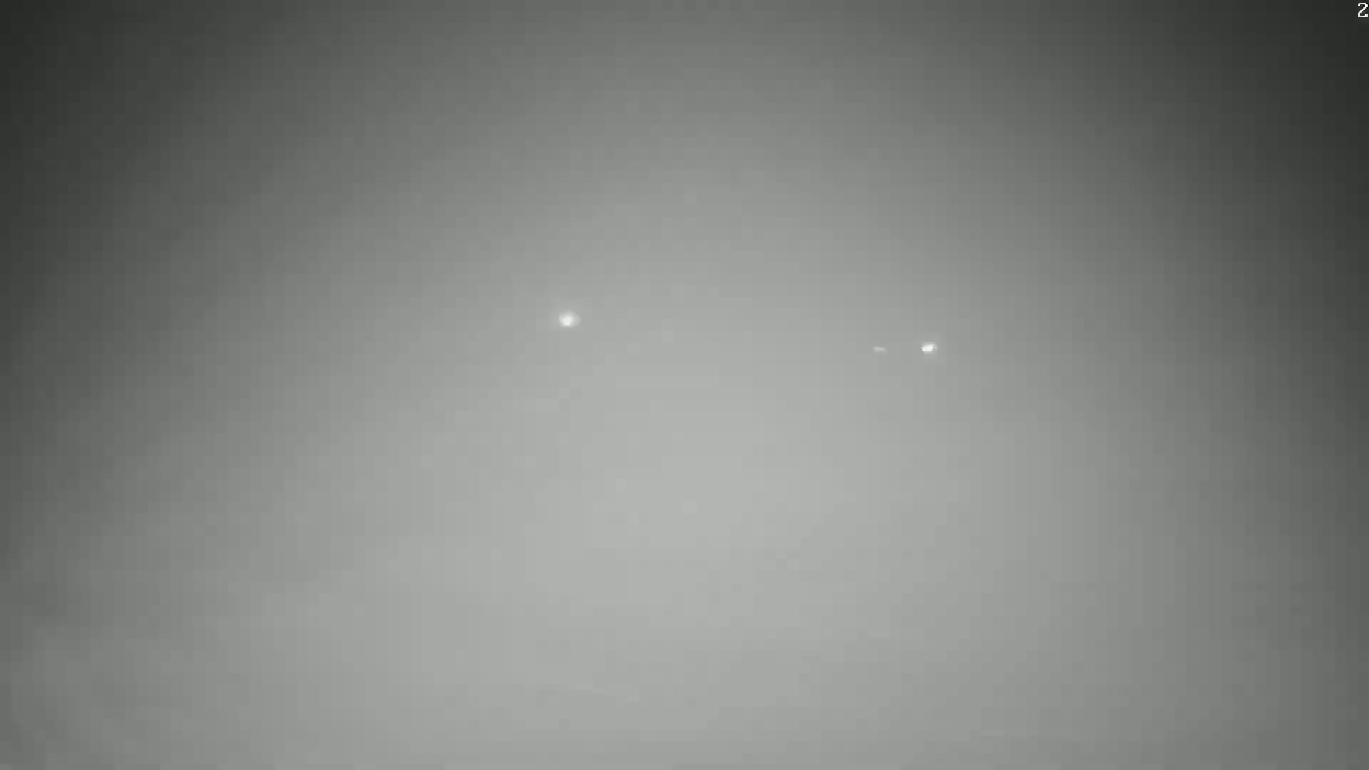 Two faint lights are visible in a hazy, gray atmosphere.