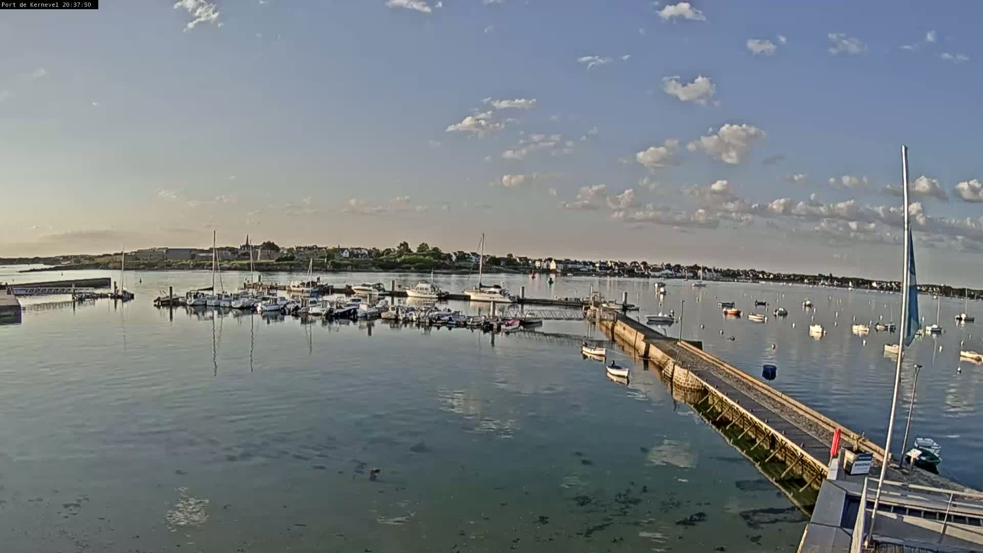 A calm harbor filled with numerous boats under a partly cloudy sky.