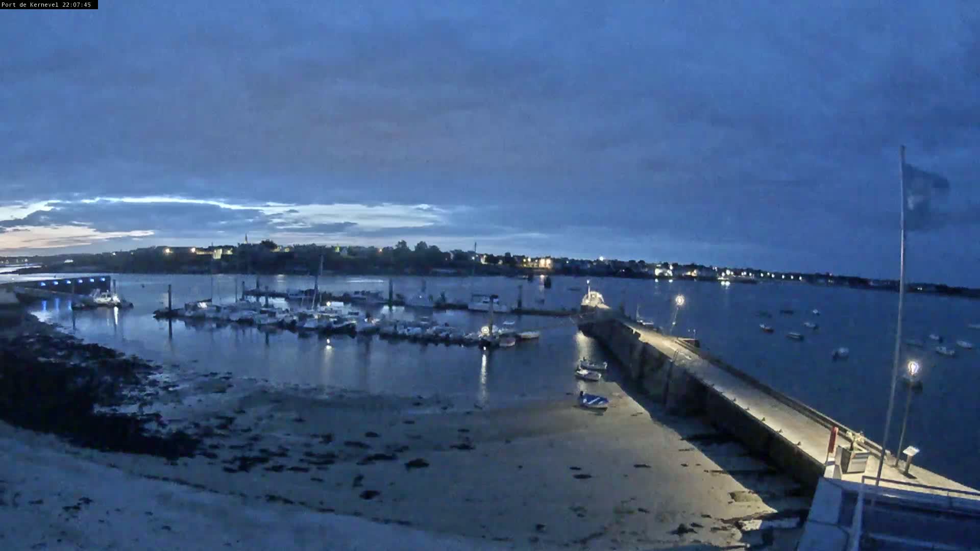 A marina filled with boats is visible at twilight under a mostly cloudy sky.