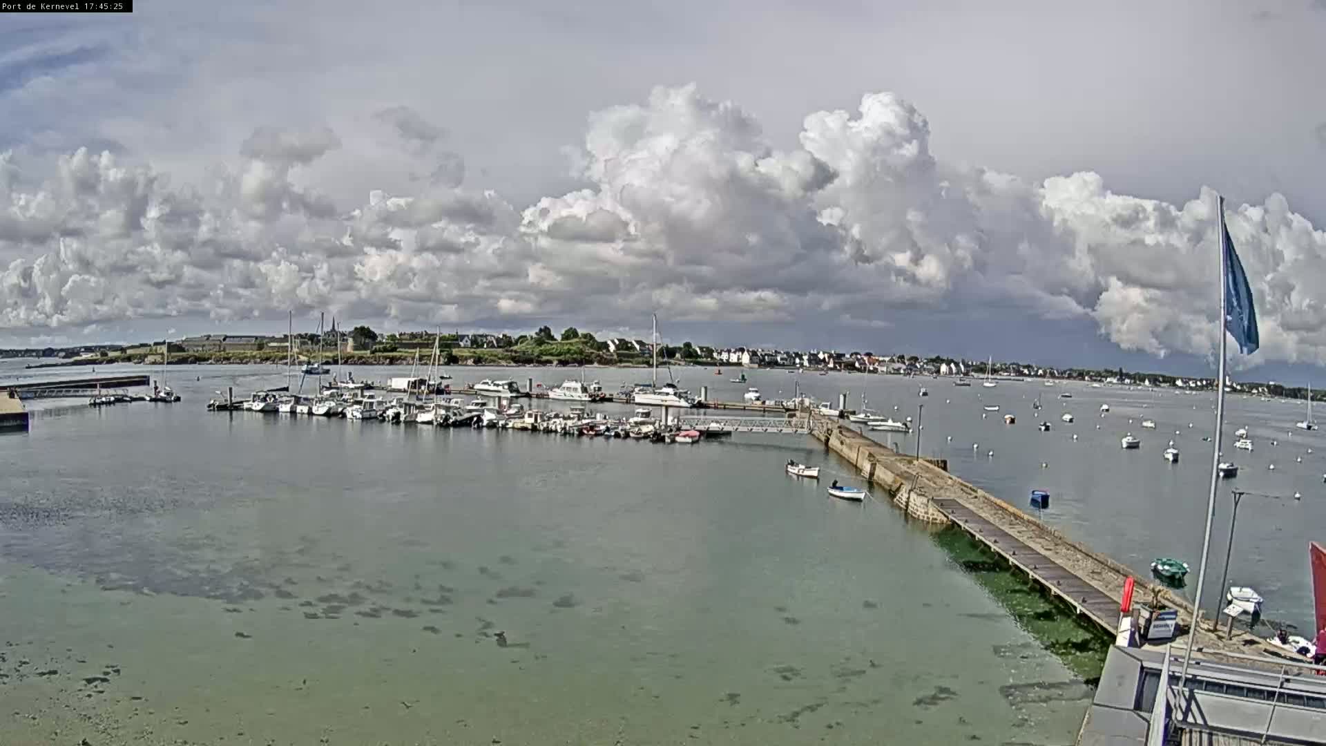A harbor filled with numerous boats is seen under a partly cloudy sky.