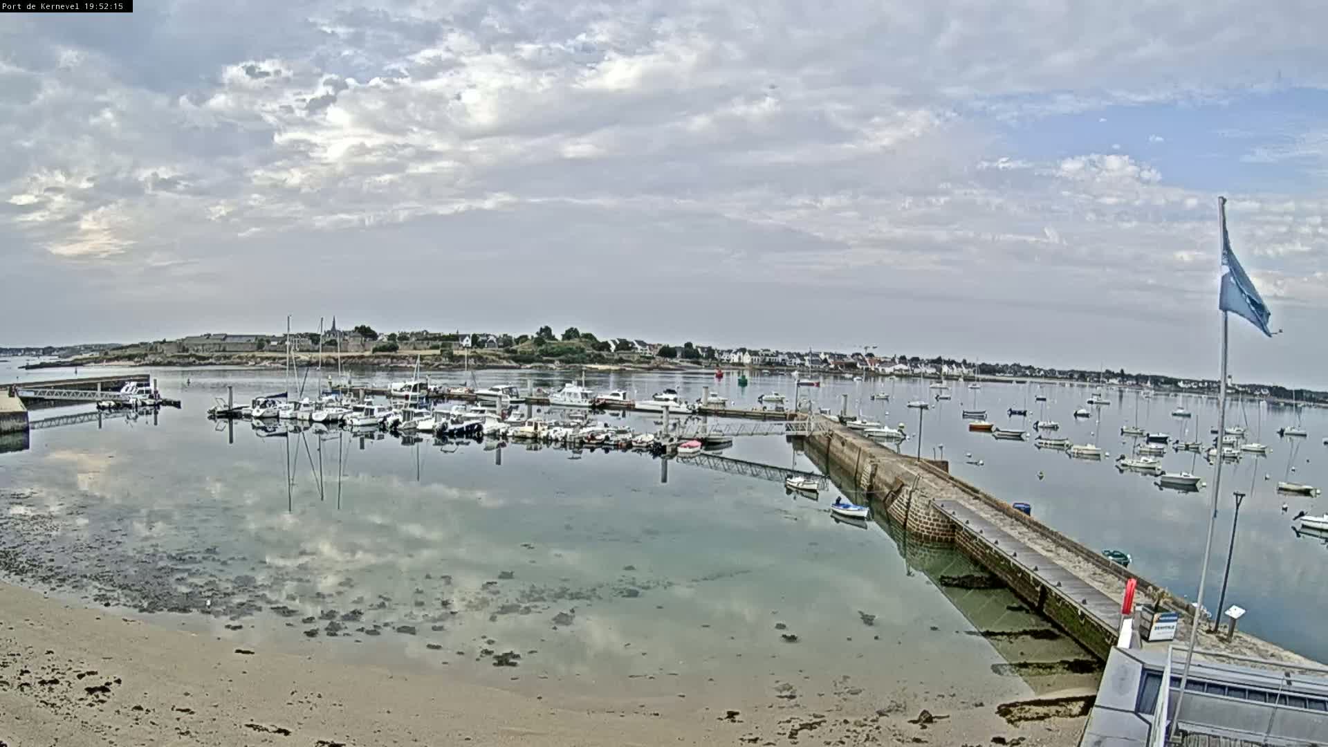 A harbor filled with sailboats and motorboats under a partly cloudy sky.