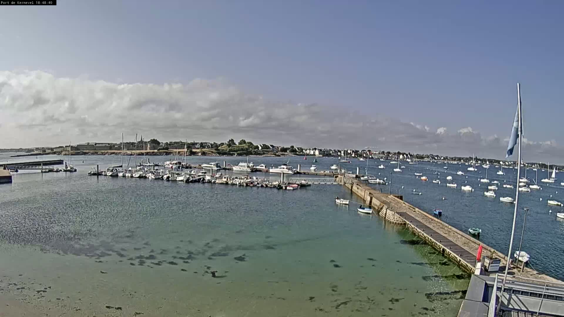 A harbor filled with numerous boats under a partly cloudy sky.