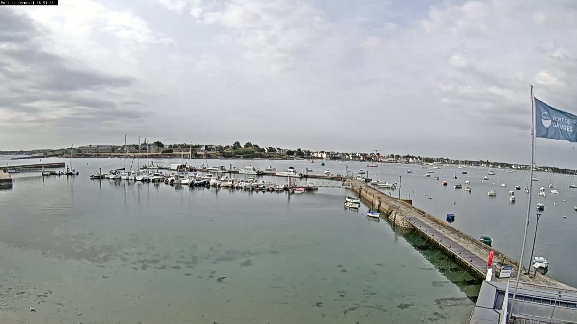 A harbor filled with numerous boats under a partly cloudy sky.