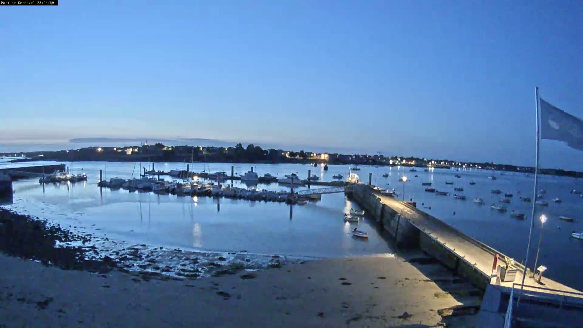 A harbor filled with numerous boats is seen under a partly cloudy sky.