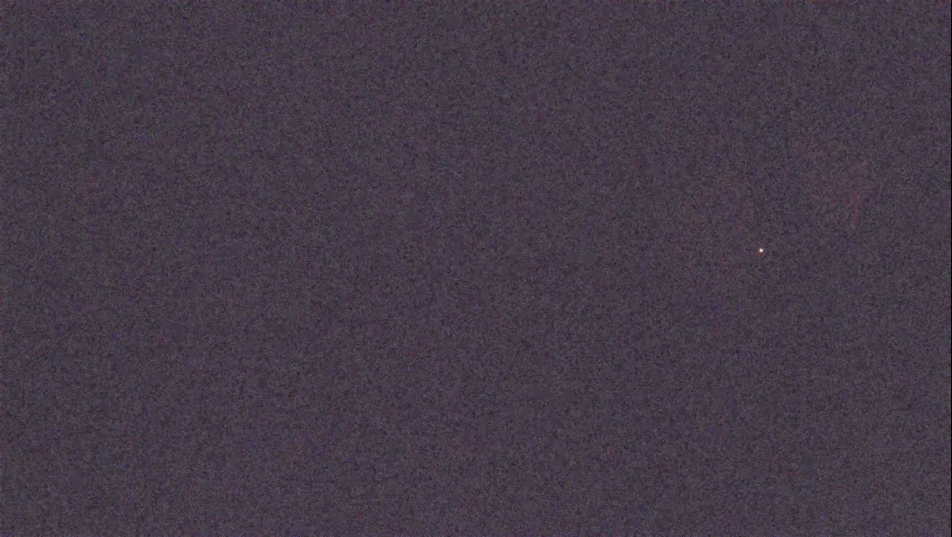 A dark purplish-gray textured background features a single, small, bright light source.