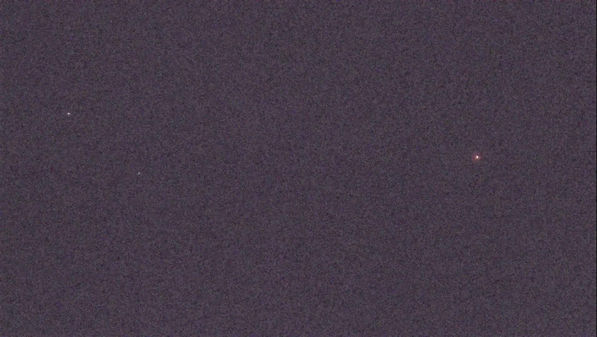 A dark night sky shows three faint stars and a brighter, reddish point of light.