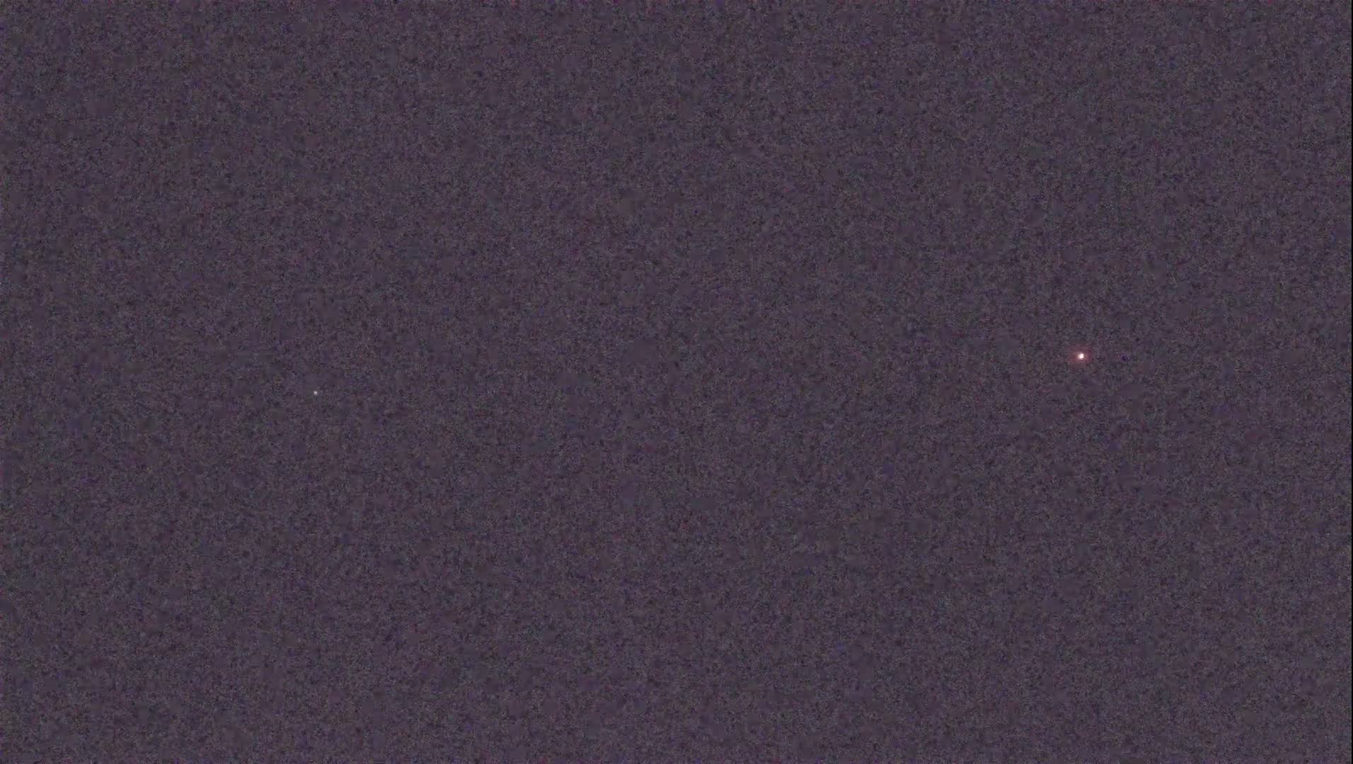 A dark, night sky shows two small, faint points of light.