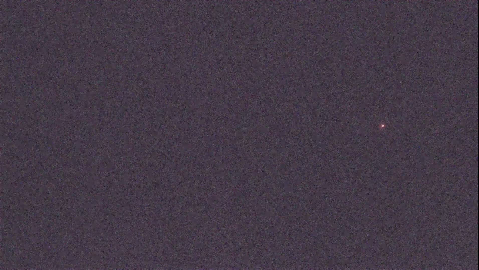 A single, faint, reddish light is visible against a dark, night sky.