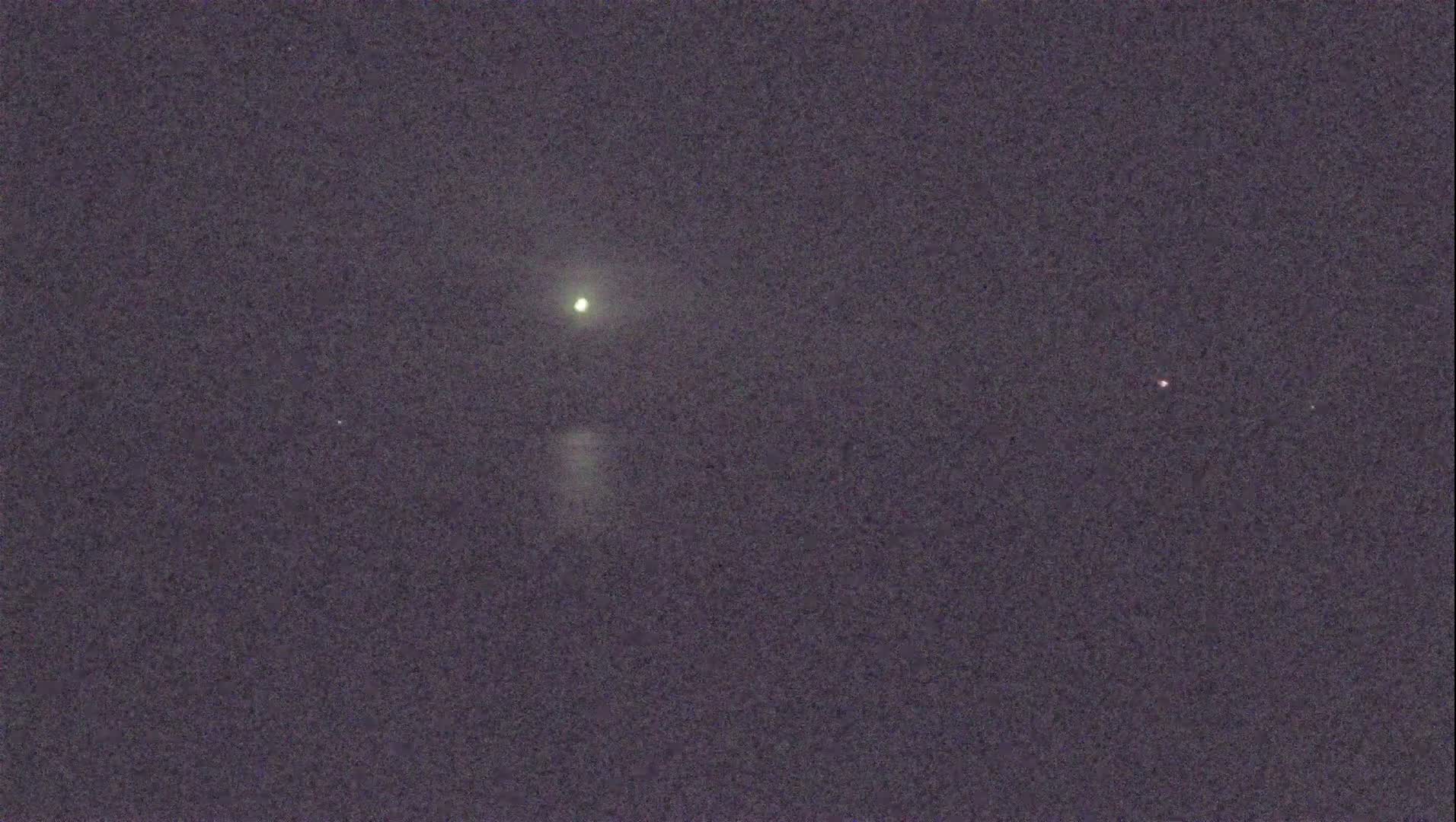 A nighttime sky shows a bright light, possibly a planet or star, and two dimmer lights.