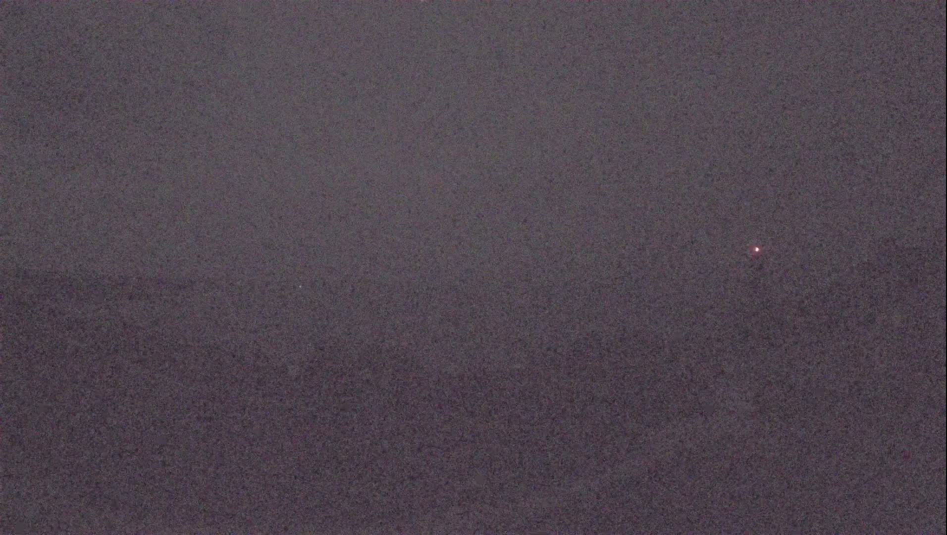 A dark, possibly nighttime, image shows a single, small, faint light in the distance.