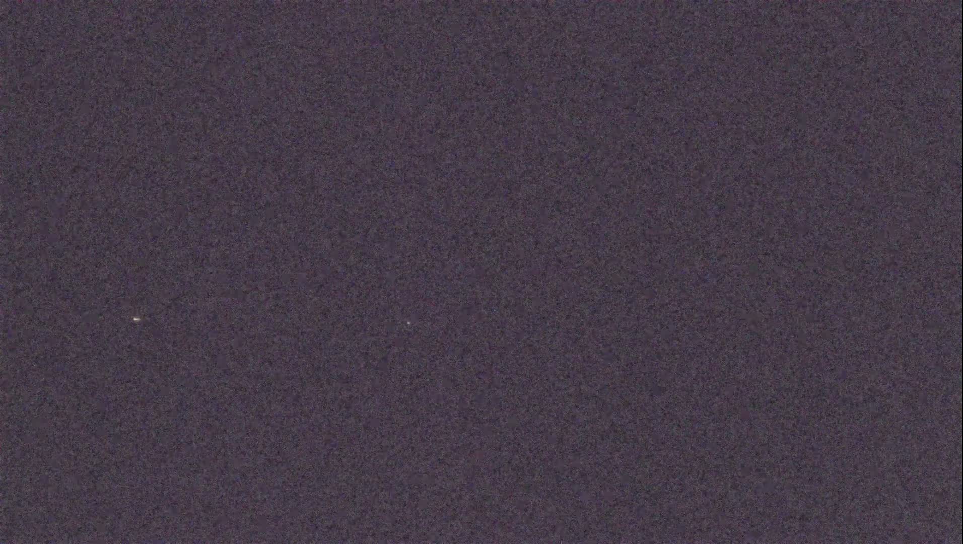 A dark, grainy image shows two faint points of light in the night sky.