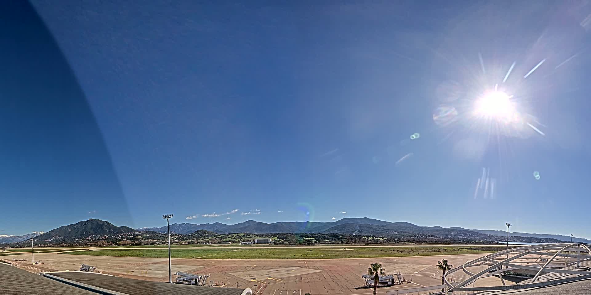 A sunny day at an airport overlooking a mountain range.